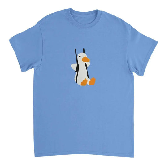 Light blue T-shirt featuring an adorable graphic of a penguin with outstretched wings and bright orange feet, hanging from black straps as if on a swing. The playful design adds a whimsical touch, making it a fun and cozy casual wear option.