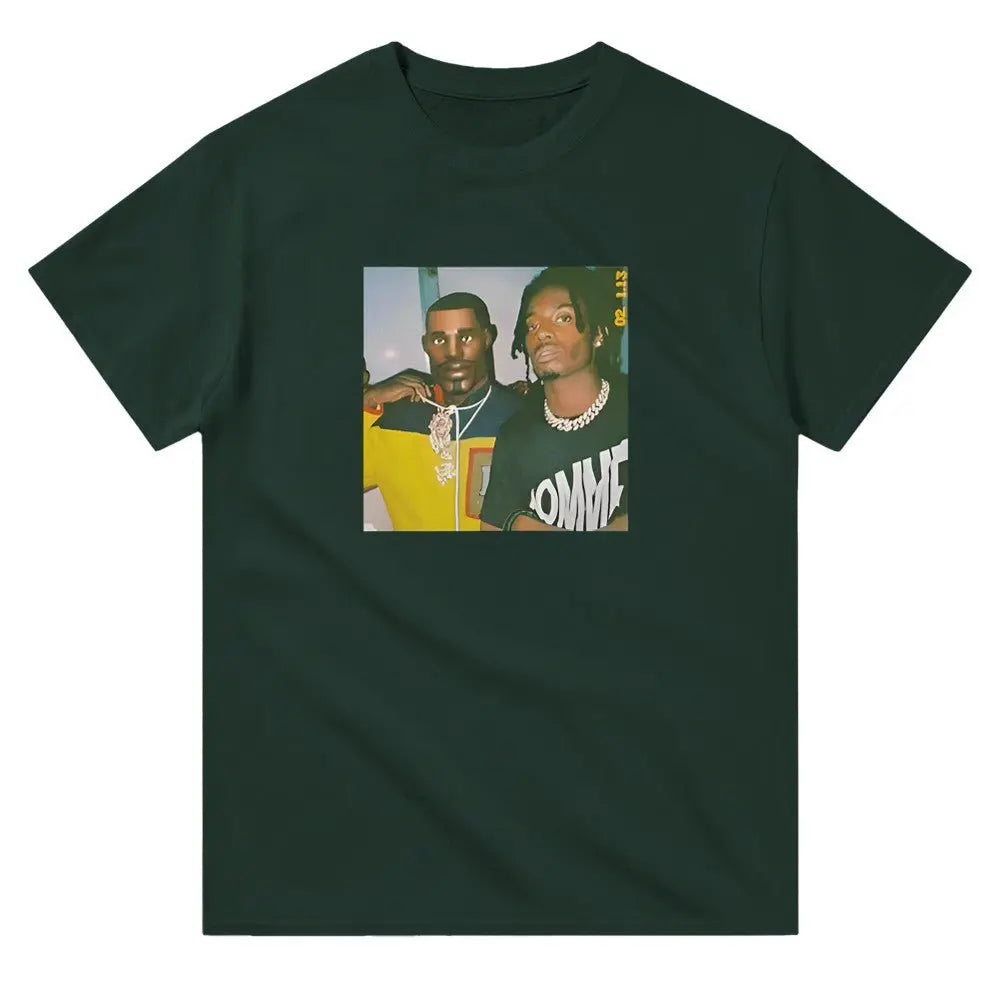 Green T-shirt displaying a graphic featuring two hip-hop figures, one in a yellow shirt with a prominent necklace and the other in a black shirt with bold white text. Carti Perc Battle Royale Shirt. The image has a retro, meme-inspired aesthetic, resonating with fans of hip-hop culture and playful streetwear fashion.