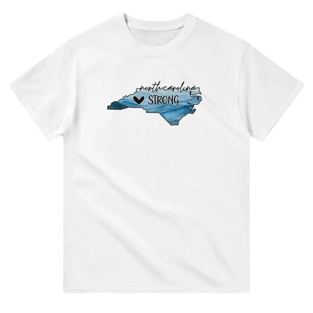 White T-shirt featuring an outline of North Carolina filled with blue and green tones, symbolizing a resilient landscape. Above the shape, the text reads "North Carolina" in a cursive font, with "STRONG" written below alongside a small heart icon. This design conveys a message of support and resilience, possibly for hurricane relief efforts.