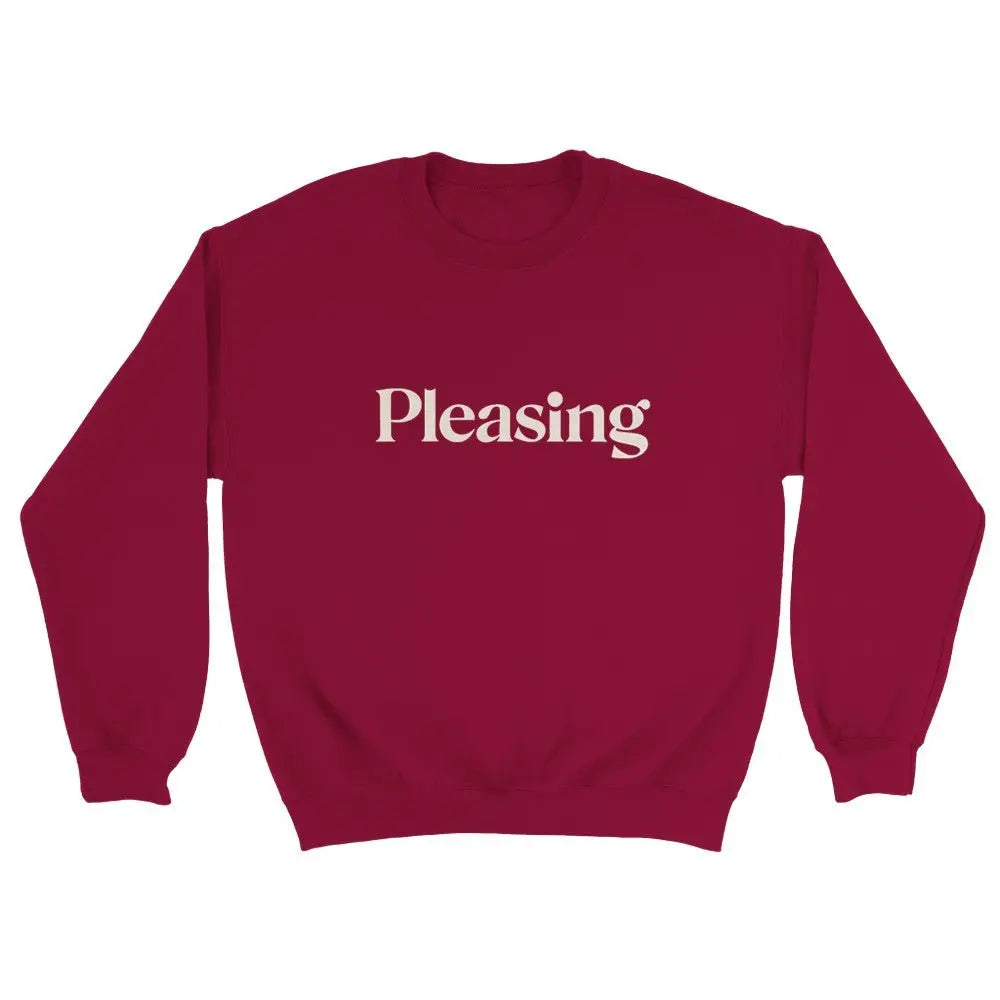 Red sweatshirt featuring the word "Pleasing" in a stylish, serif font across the chest. The minimalist design references the branding associated with Harry Styles, appealing to fans of his aesthetic and brand. The overall look is simple yet trendy.