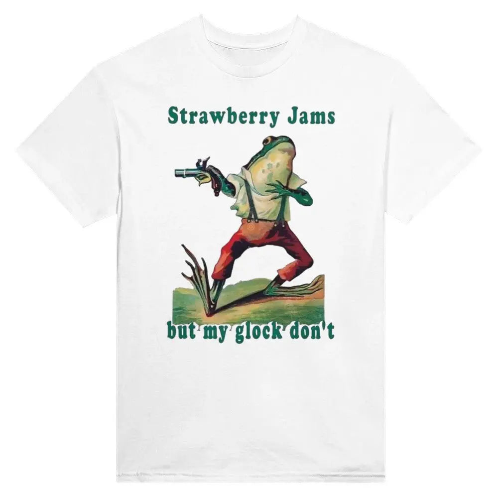 White T-shirt featuring a humorous illustration of a frog dressed in vintage-style clothing, holding a gun. Above the frog, the text reads, "Strawberry Jams," and below it says, "but my glock don't," in a playful, retro font. The design combines whimsical art with a tongue-in-cheek message.