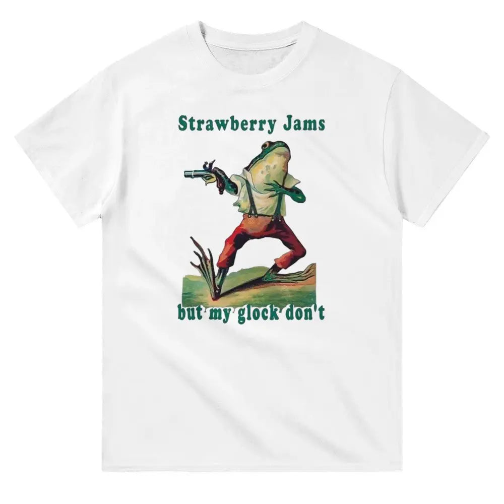 White T-shirt featuring a humorous illustration of a frog dressed in vintage-style clothing, holding a gun. Above the frog, the text reads, "Strawberry Jams, but my glock don't," in a playful, retro font. The design combines whimsical art with a tongue-in-cheek message.